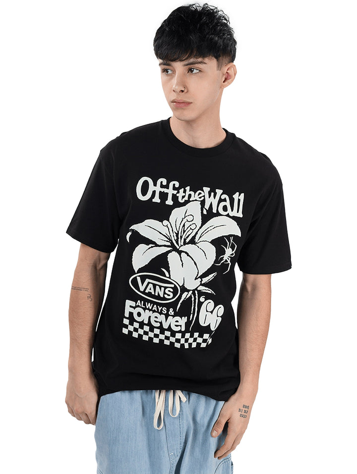 Hombre vistiendo camiseta negra VANS de manga corta con gráfico blanco de una flor y texto.