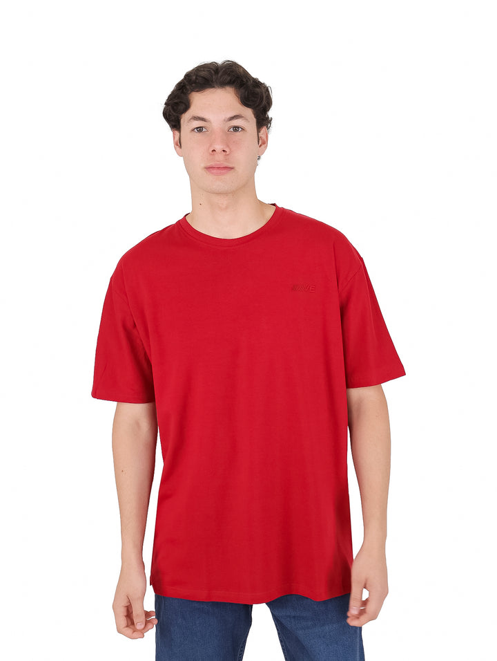 Hombre vistiendo una playera roja de manga corta y cuello redondo.