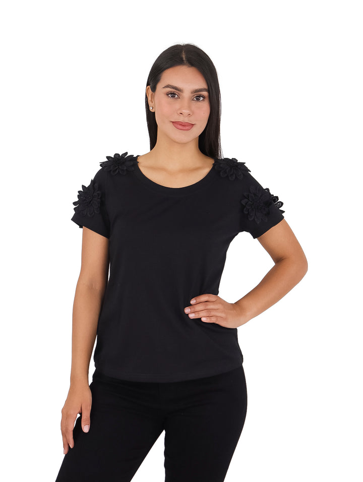 Mujer vistiendo blusa negra de manga corta con detalles de flores en los hombros.