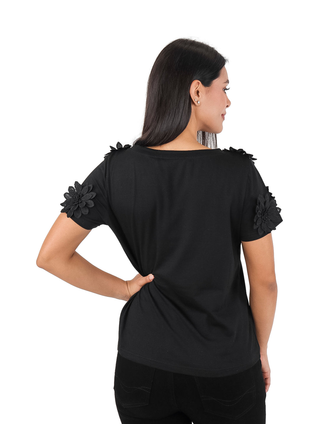 Mujer vistiendo blusa negra de manga corta con detalles de flores en los hombros.