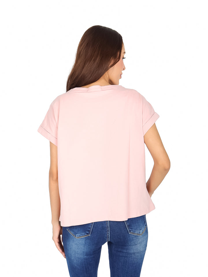 Mujer vistiendo blusa rosa de manga corta con detalles brillantes en forma de V en el pecho.