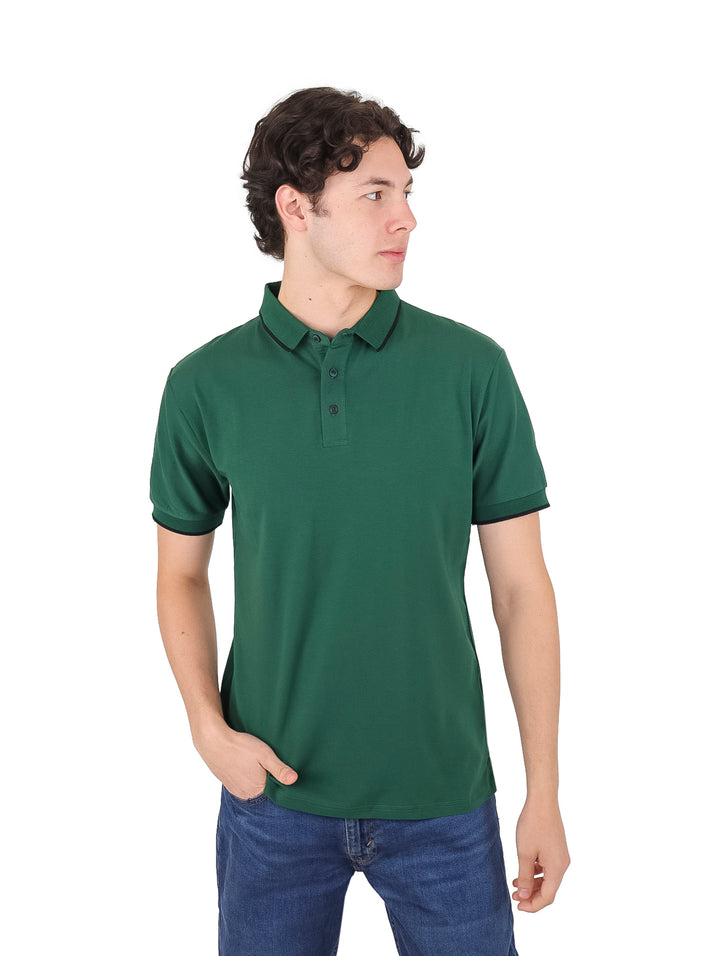 Hombre vistiendo una playera polo de color verde oscuro con detalles negros en los bordes.