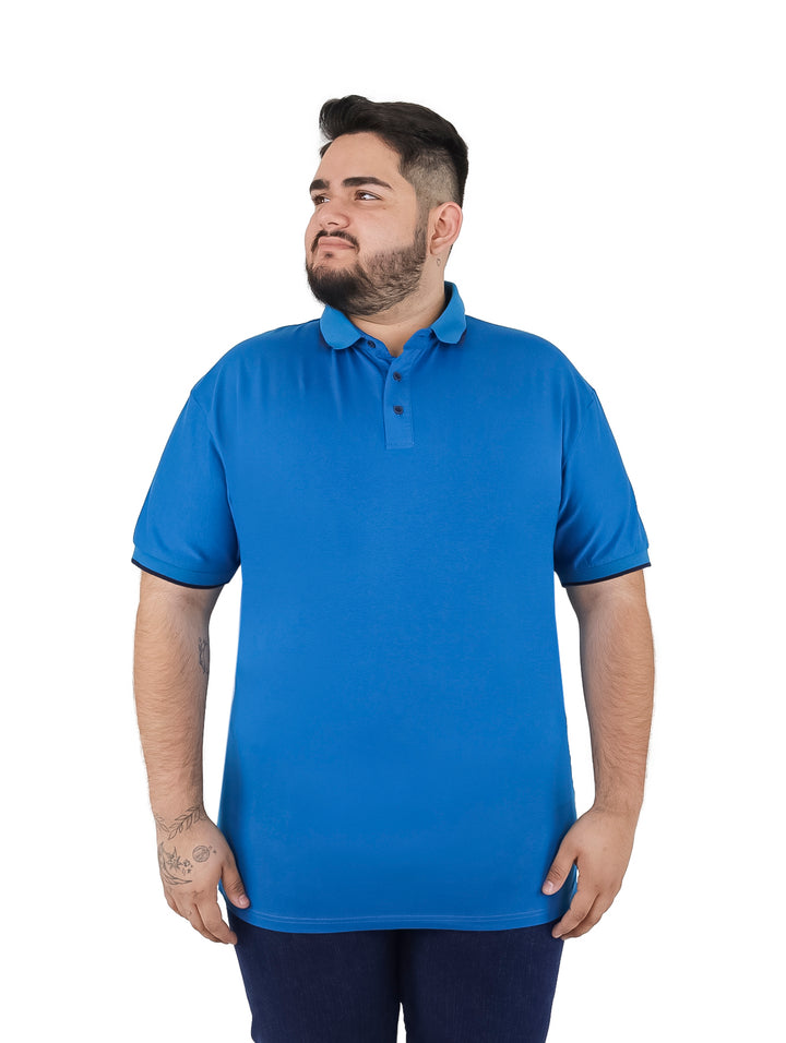 Hombre vistiendo una playera polo color azul con detalles en azul marino en el cuello y mangas.