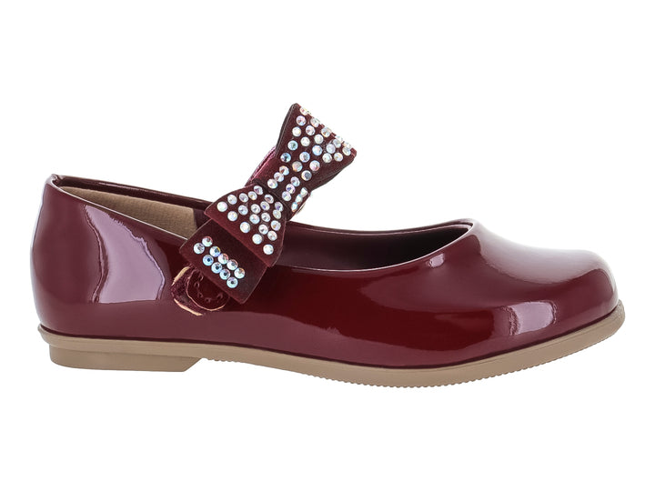Zapato plano de charol color vino para niña con moño decorado con pedrería brillante y suela beige.