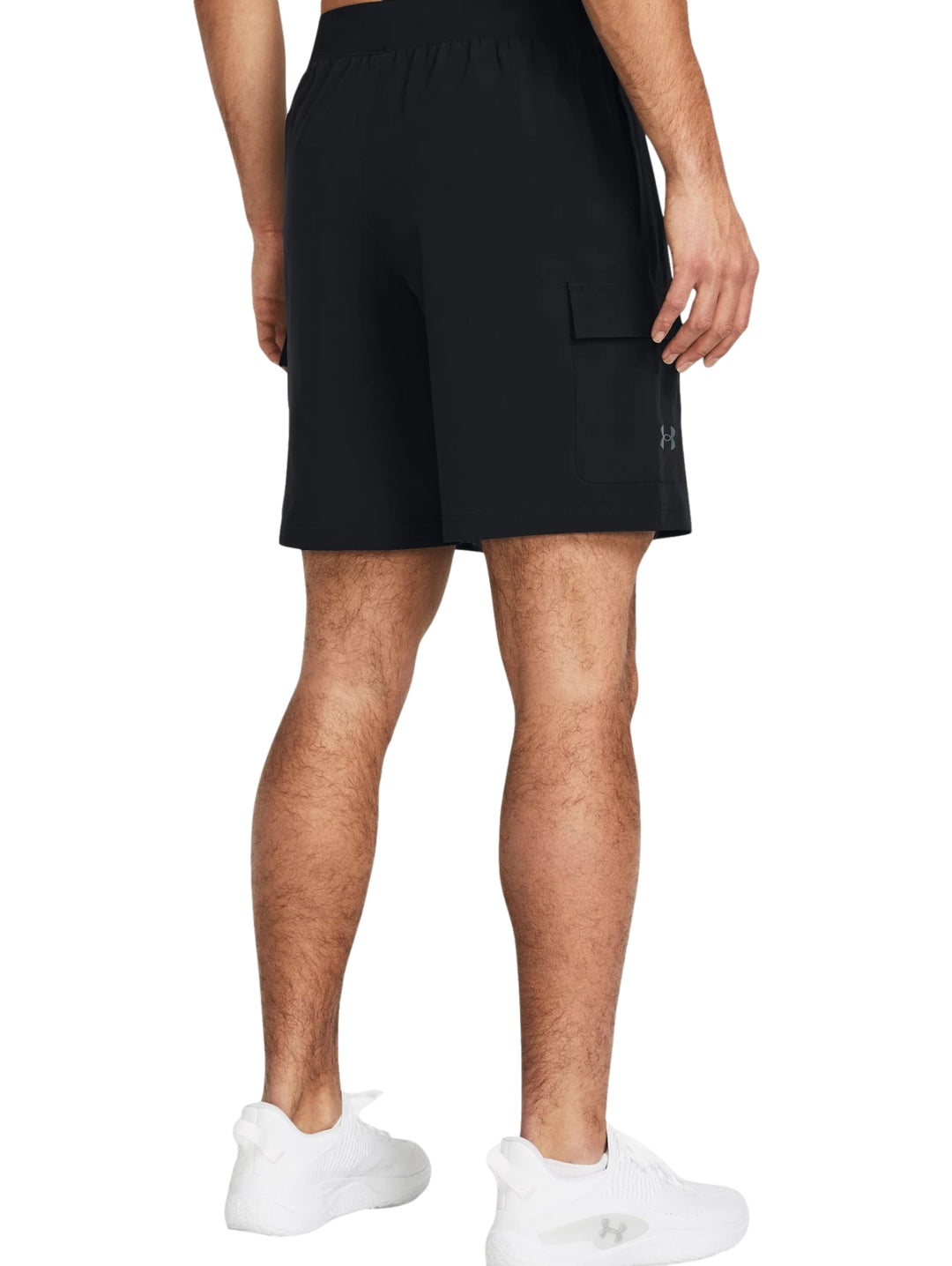 Hombre vistiendo shorts deportivos cargo de color negro marca Under Armour con camiseta blanca y tenis blancos.