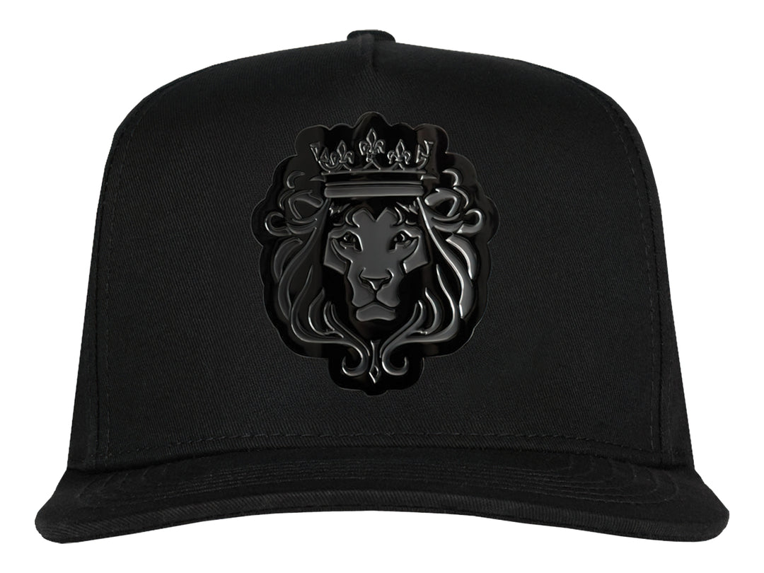 Gorra snapback color negro con un parche frontal detallado de la cabeza de un león con corona en tonos negros y grises.