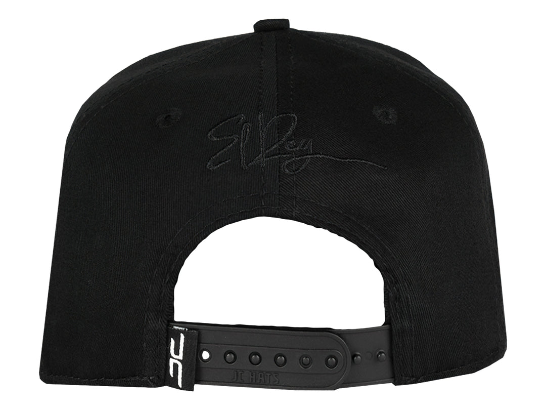 Gorra snapback color negro con un parche frontal detallado de la cabeza de un león con corona en tonos negros y grises.