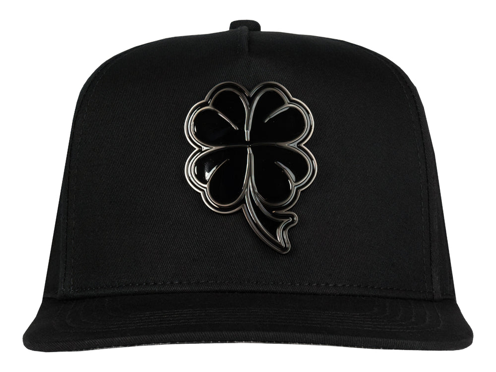 Gorra snapback color negro con un logo de trébol brillante en el frente.