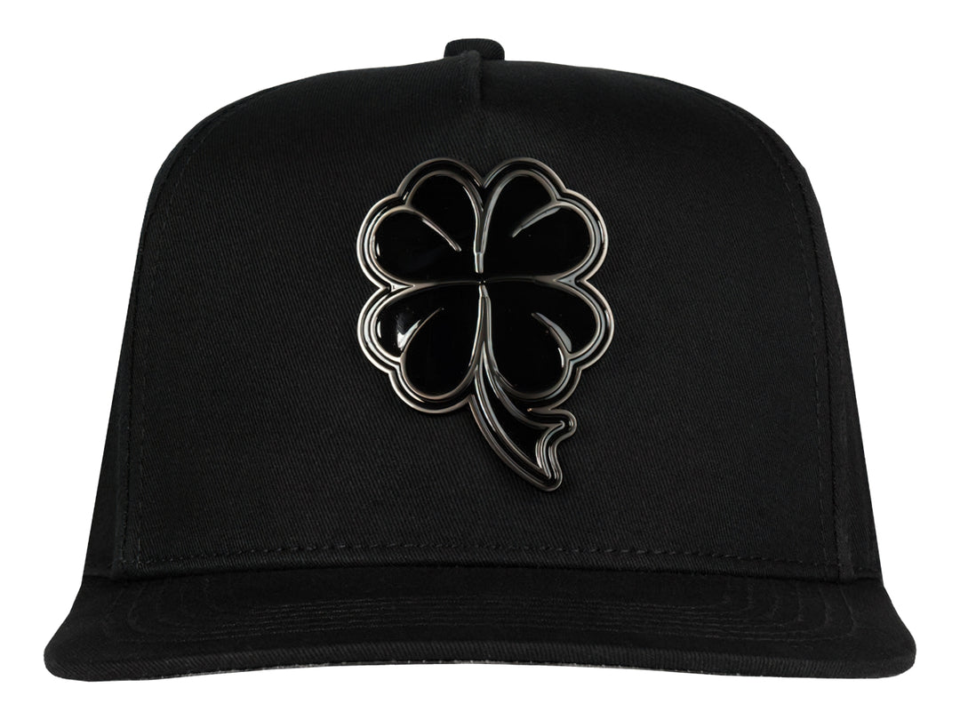 Gorra snapback color negro con un logo de trébol brillante en el frente.