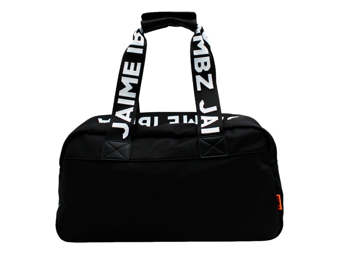 Maletín negro de Jaime Ibiza con asas anchas y un accesorio colgante color naranja, porté por una mujer.