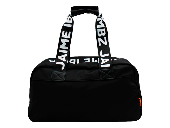 Maletín negro de Jaime Ibiza con asas anchas y un accesorio colgante color naranja, porté por una mujer.