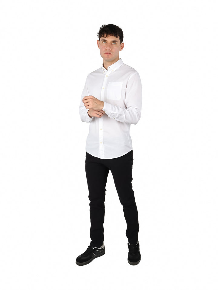Hombre vistiendo una camisa Oxford de color blanco con manga larga y un bolsillo en el pecho.