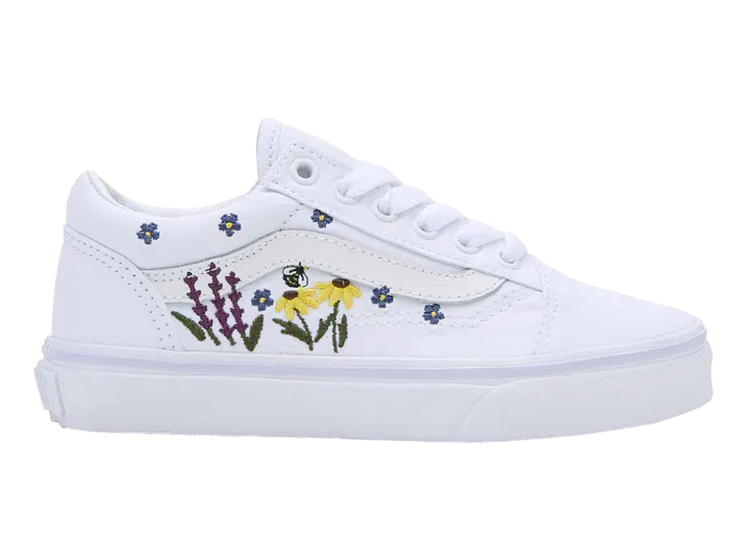 Tenis Vans blancos con bordados de flores coloridas en los laterales.