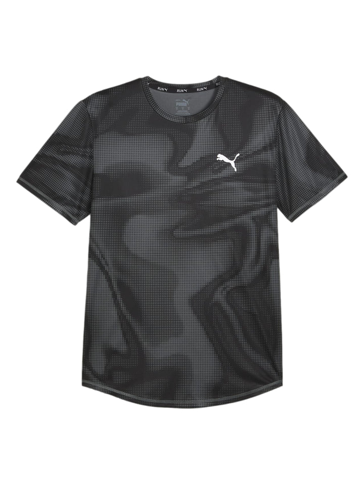 Hombre vistiendo camiseta deportiva Puma negra con estampado de puntos y shorts verdes.