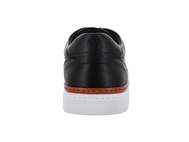 Tenis casuales de cuero negro con suela blanca y una línea decorativa marrón en la base.