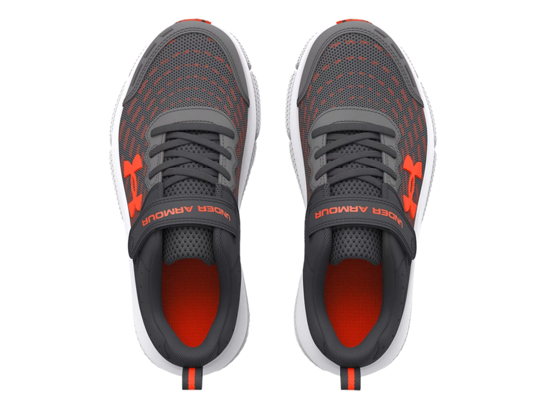 Tenis deportivos Under Armour color gris con detalles en naranja y suela blanca.