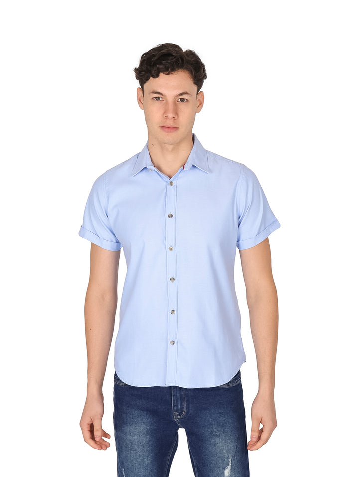 Hombre vistiendo una camisa de manga corta color azul cielo con botones frontales.