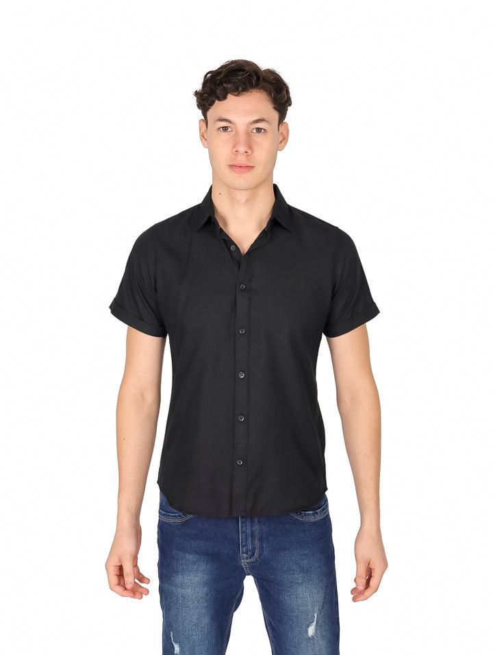Hombre vistiendo una camisa negra de manga corta con botones y pantalones jeans azules.