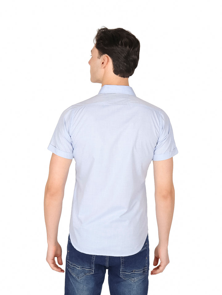 Hombre vistiendo una camisa de manga corta color azul cielo y pantalones de mezclilla.