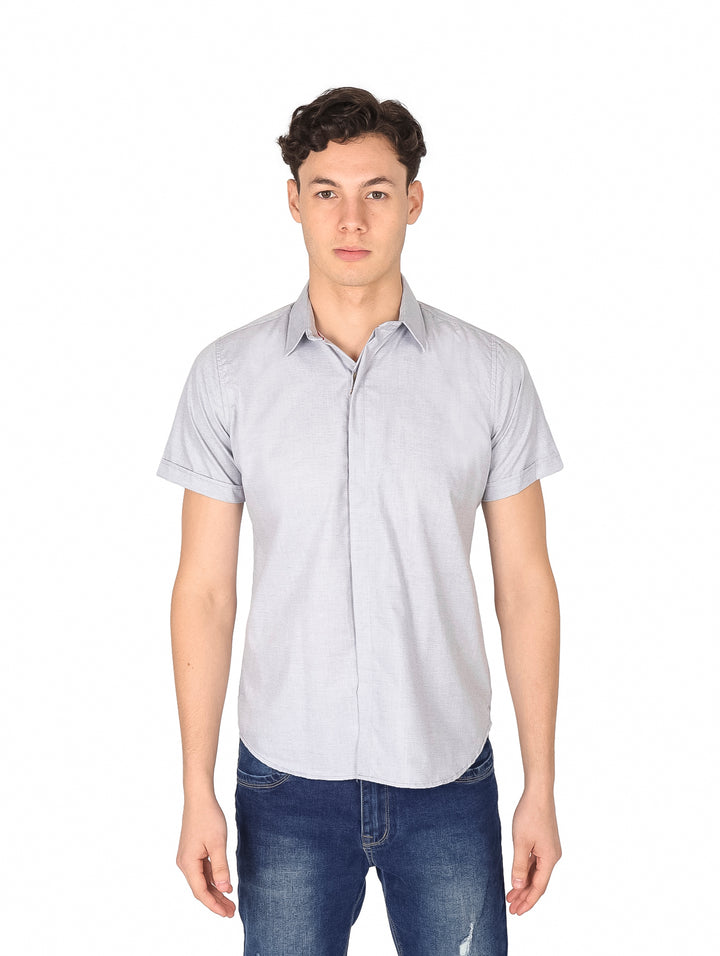 Hombre vistiendo una camisa casual de color gris con manga corta y cuello, combinada con jeans azules.