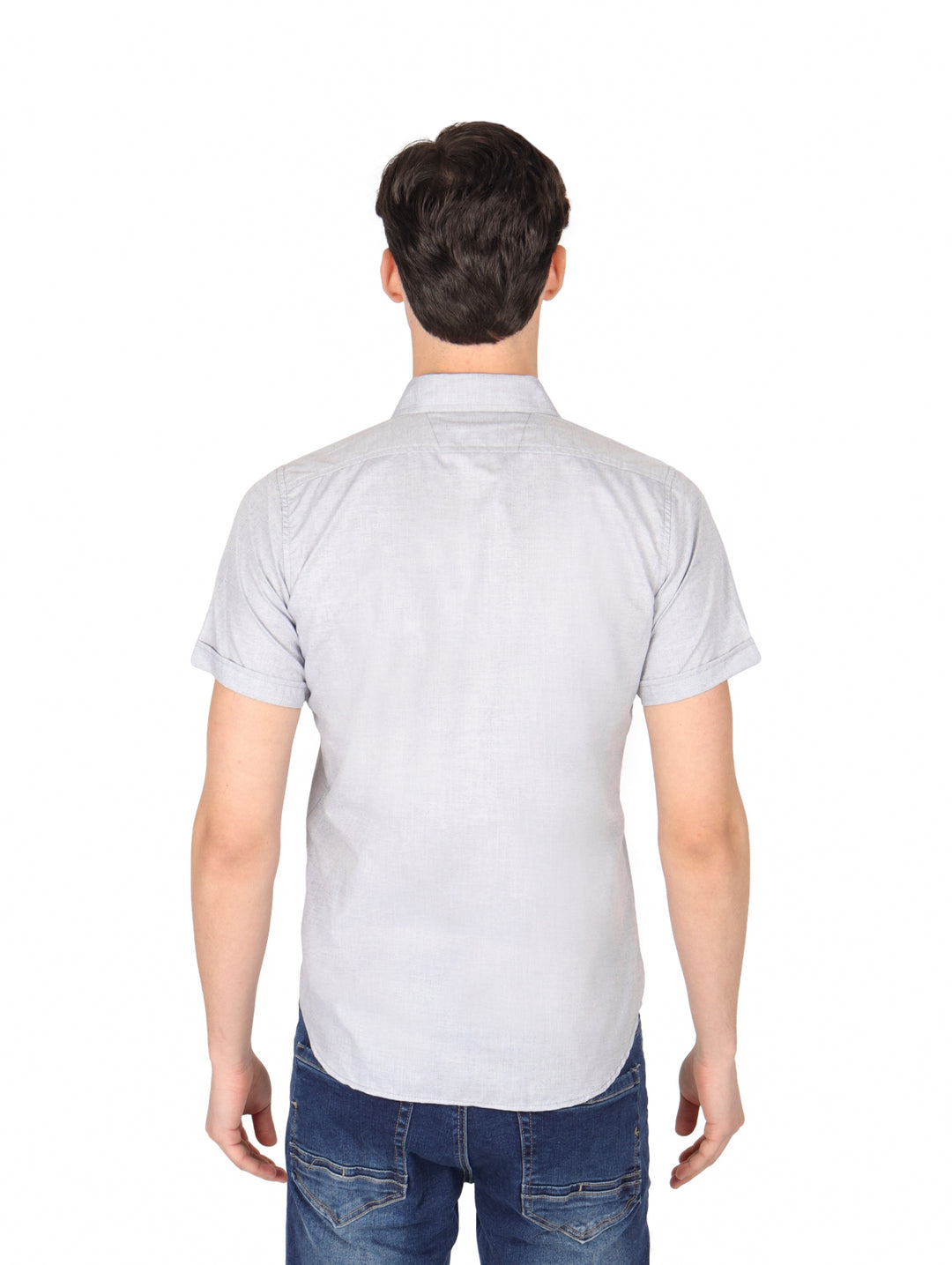 Hombre vistiendo una camisa casual de color gris con manga corta y cuello, combinada con jeans azules.