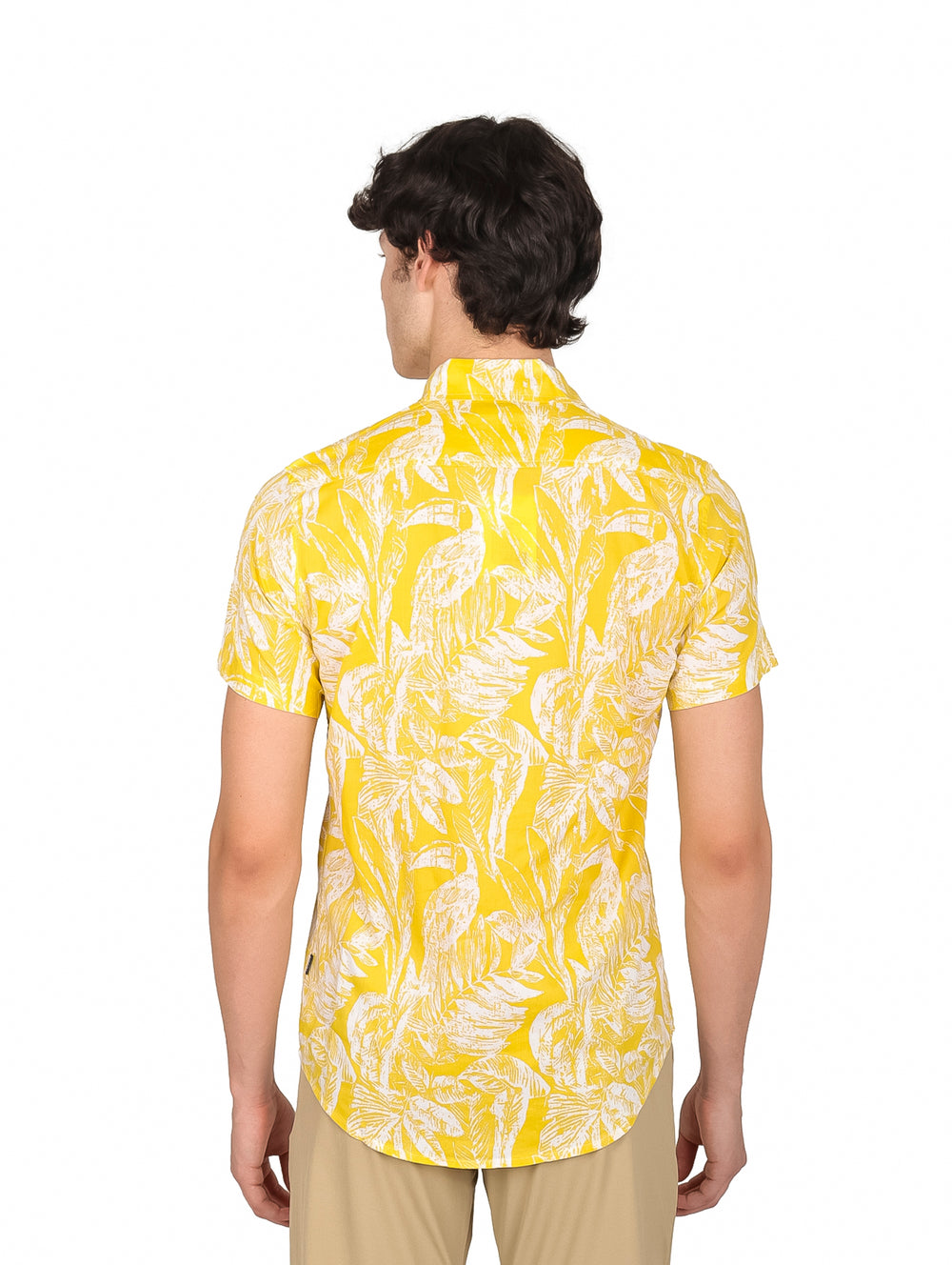 Hombre vistiendo camisa amarilla de manga corta con estampado de hojas blancas.