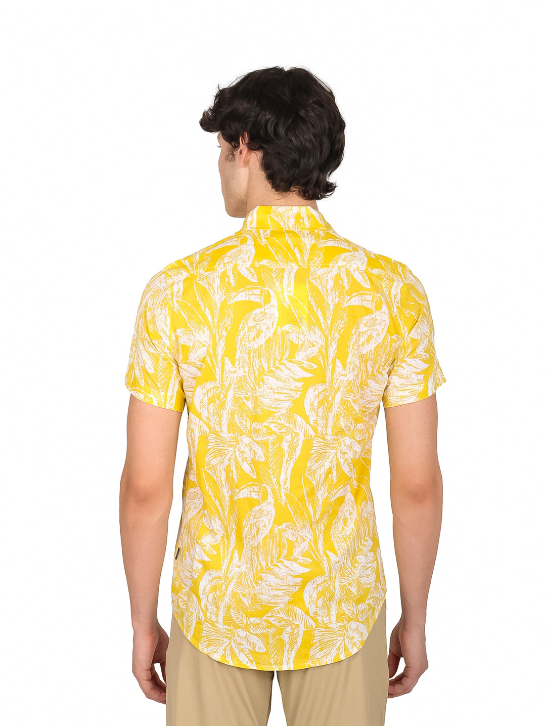 Hombre vistiendo camisa amarilla de manga corta con estampado de hojas blancas.