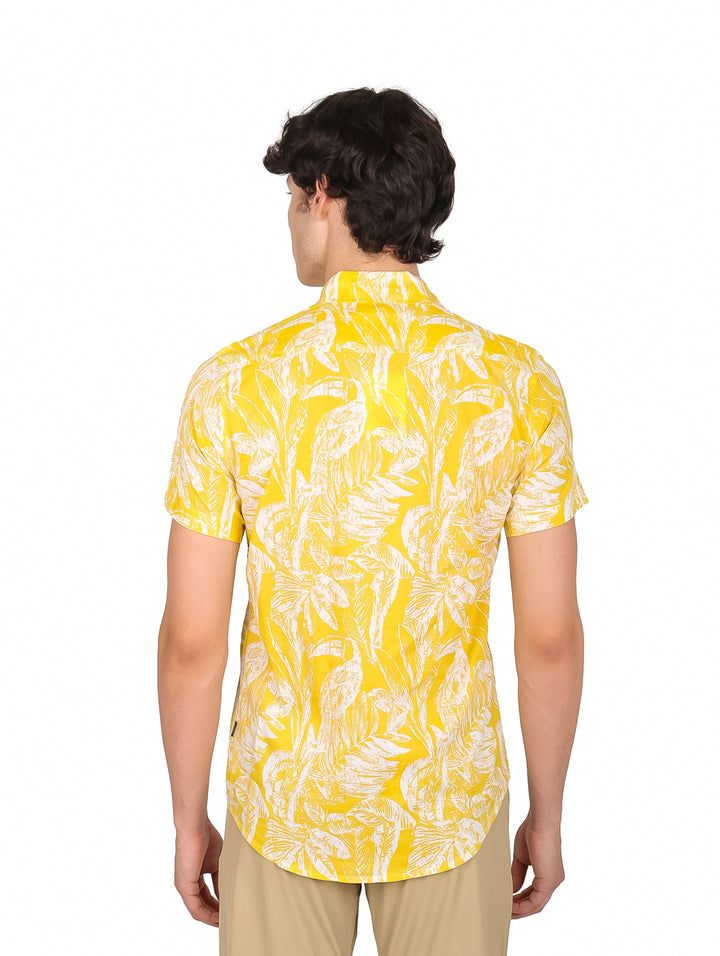 Hombre vistiendo camisa amarilla de manga corta con estampado de hojas blancas.