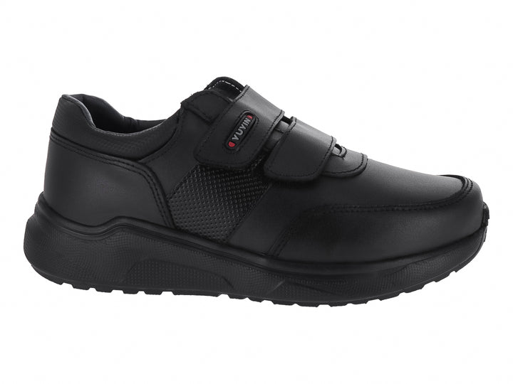 Zapato negro para niño con cierre de velcro y suela gruesa.