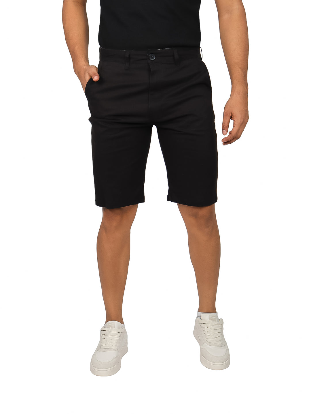 Hombre vistiendo bermudas color negro de corte casual con calzado blanco sobre fondo blanco.