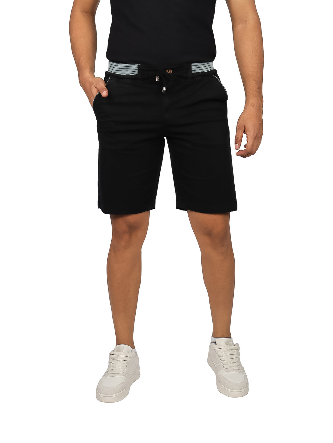 Hombre vistiendo bermudas negras casuales con cinturón a rayas y tenis blancos.