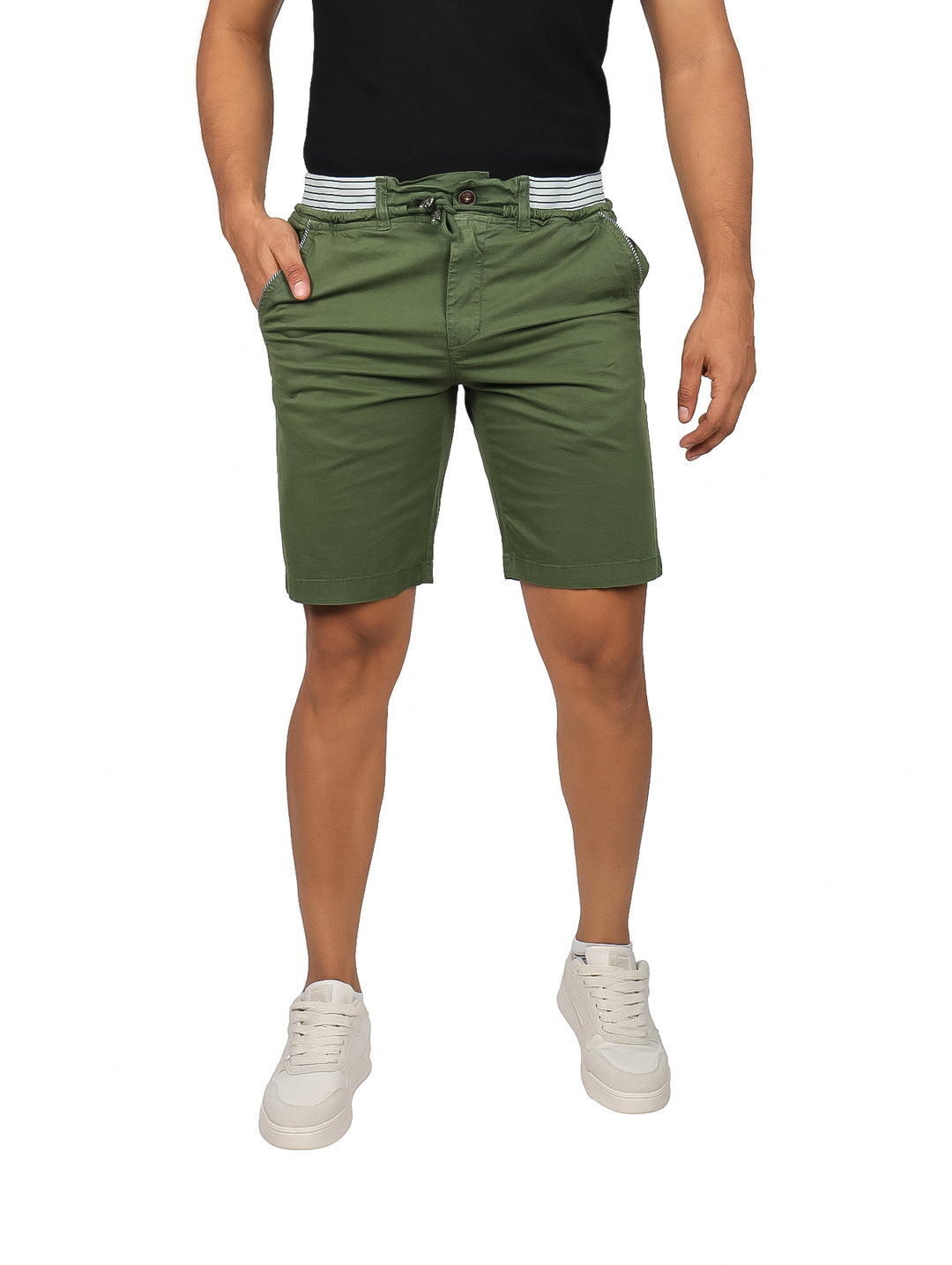 Hombre vistiendo bermudas color olivo con cintura elástica y tenis blancos.
