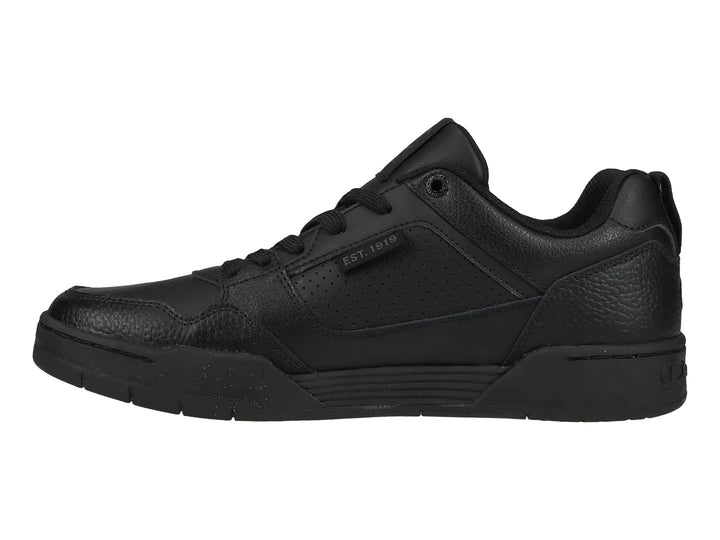 Tenis Champion color negro, corte bajo, con textura de cuero sintético y suela negra.