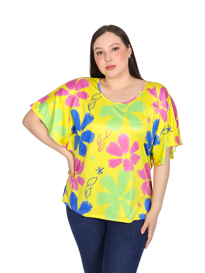 Mujer vistiendo blusa amarilla de manga corta con estampado floral en colores rosa, azul y verde.