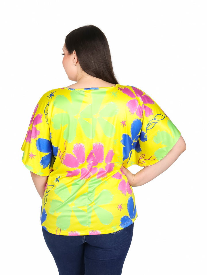 Mujer vistiendo blusa amarilla de manga corta con estampado floral en colores rosa, azul y verde.