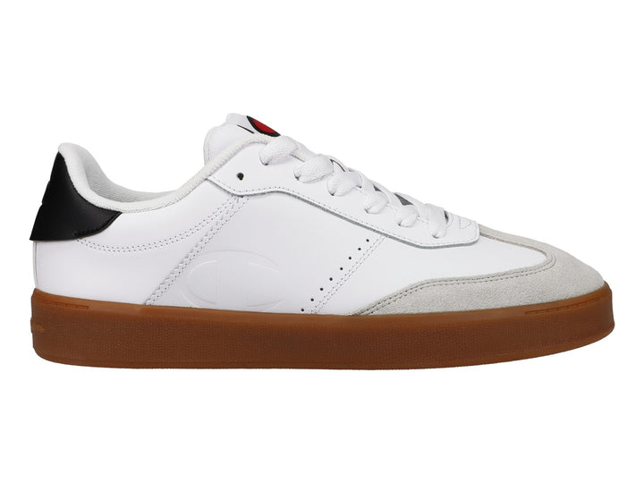 Tenis Champion blancos con suela de goma color café, punta gris y detalle negro en el talón.