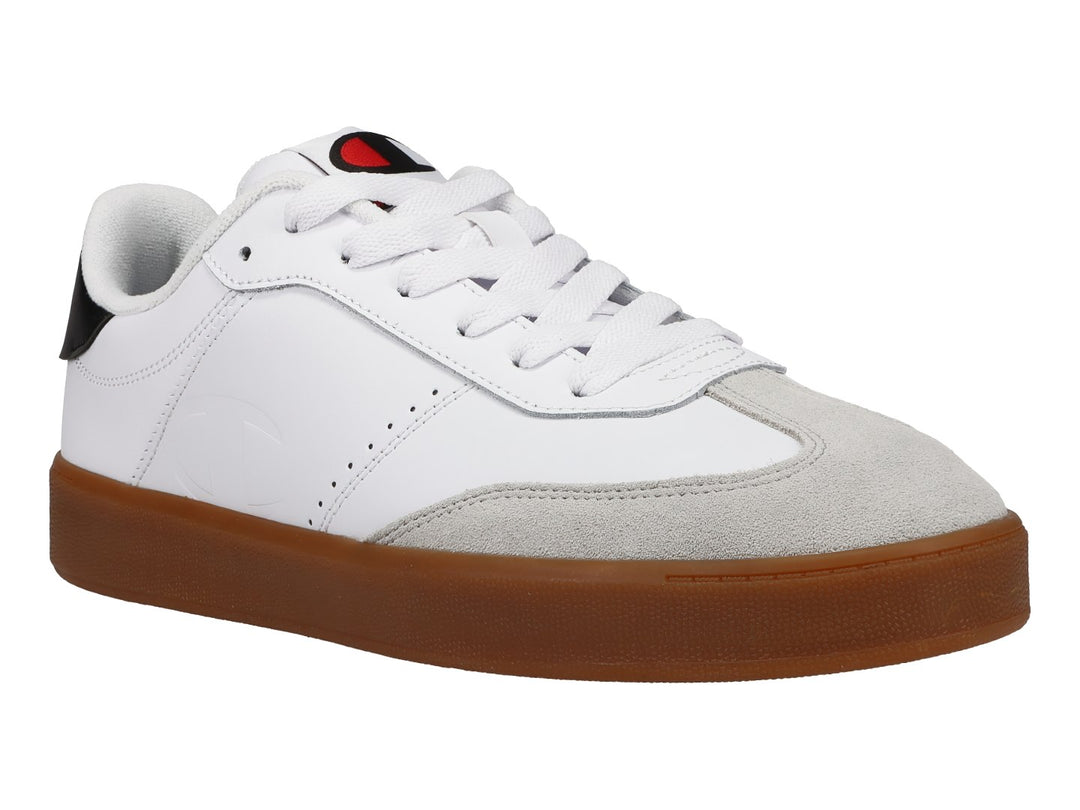 Tenis Champion blancos con suela de goma color café, punta gris y detalle negro en el talón.