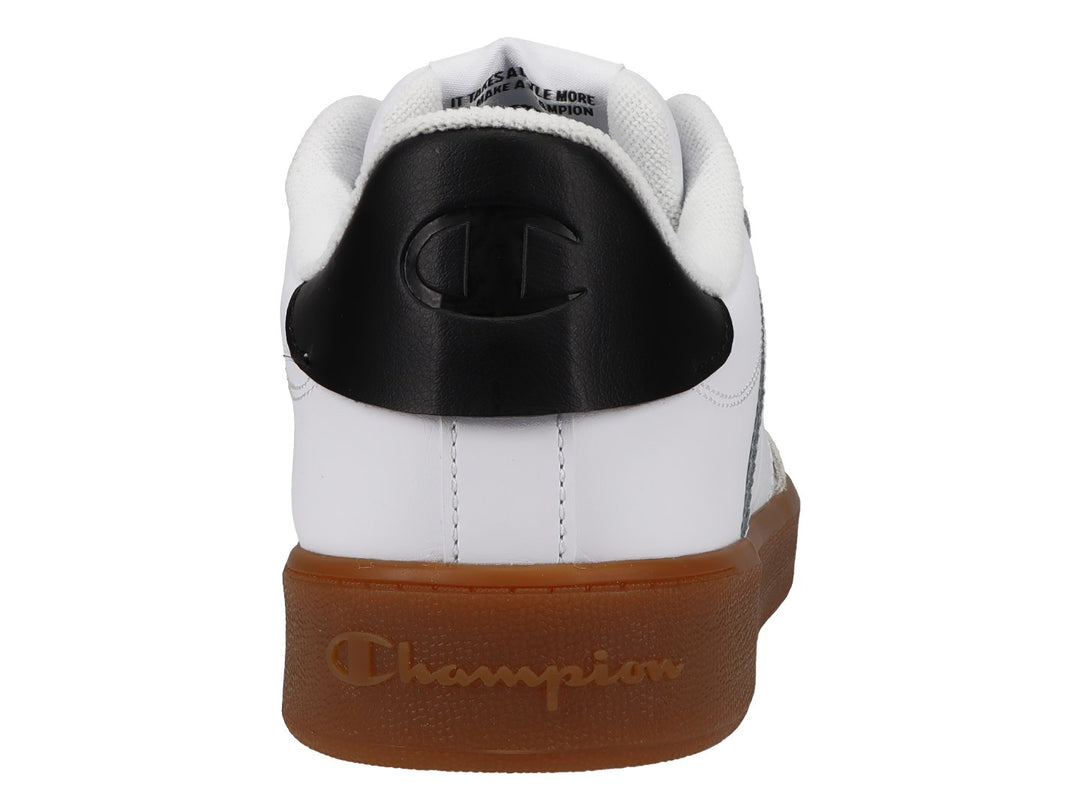 Tenis Champion blancos con suela de goma color café, punta gris y detalle negro en el talón.