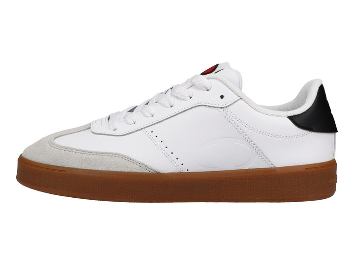 Tenis Champion blancos con suela de goma color café, punta gris y detalle negro en el talón.