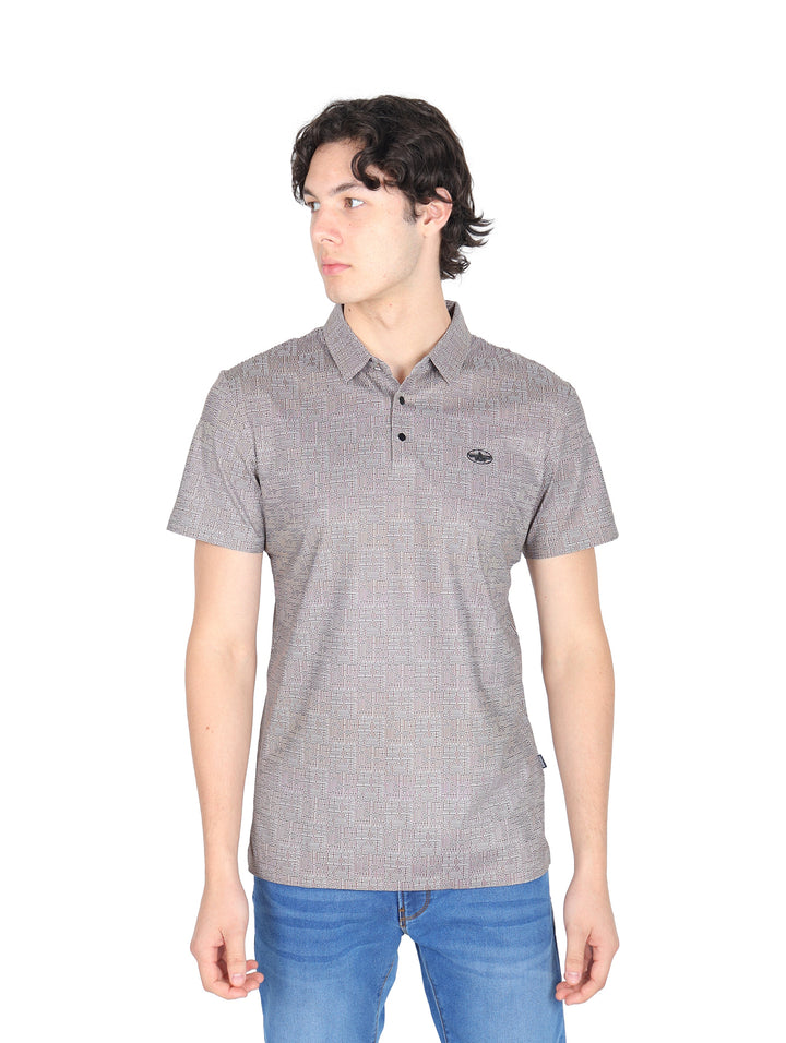 Hombre vistiendo una playera polo color café con un patrón sutil y pantalones vaqueros azules.