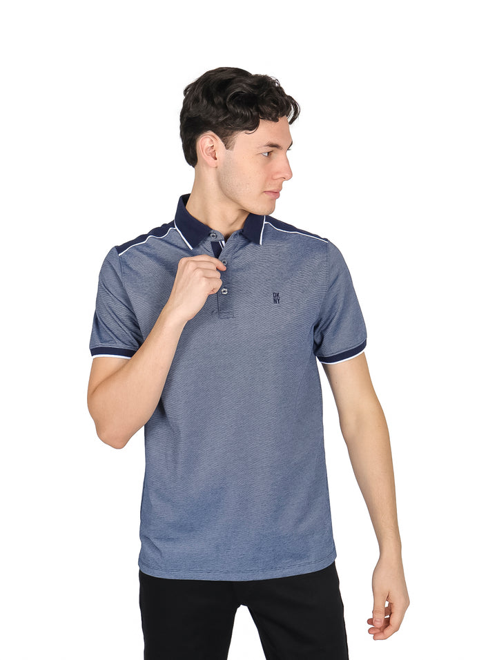 Hombre vistiendo polo DKNY color azul marino con detalles blancos en cuello y mangas.