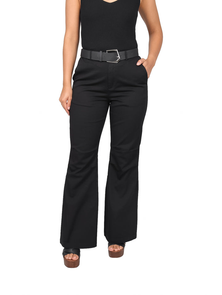 Mujer vistiendo pantalón negro de corte acampanado con cinturón negro y hebilla plateada.