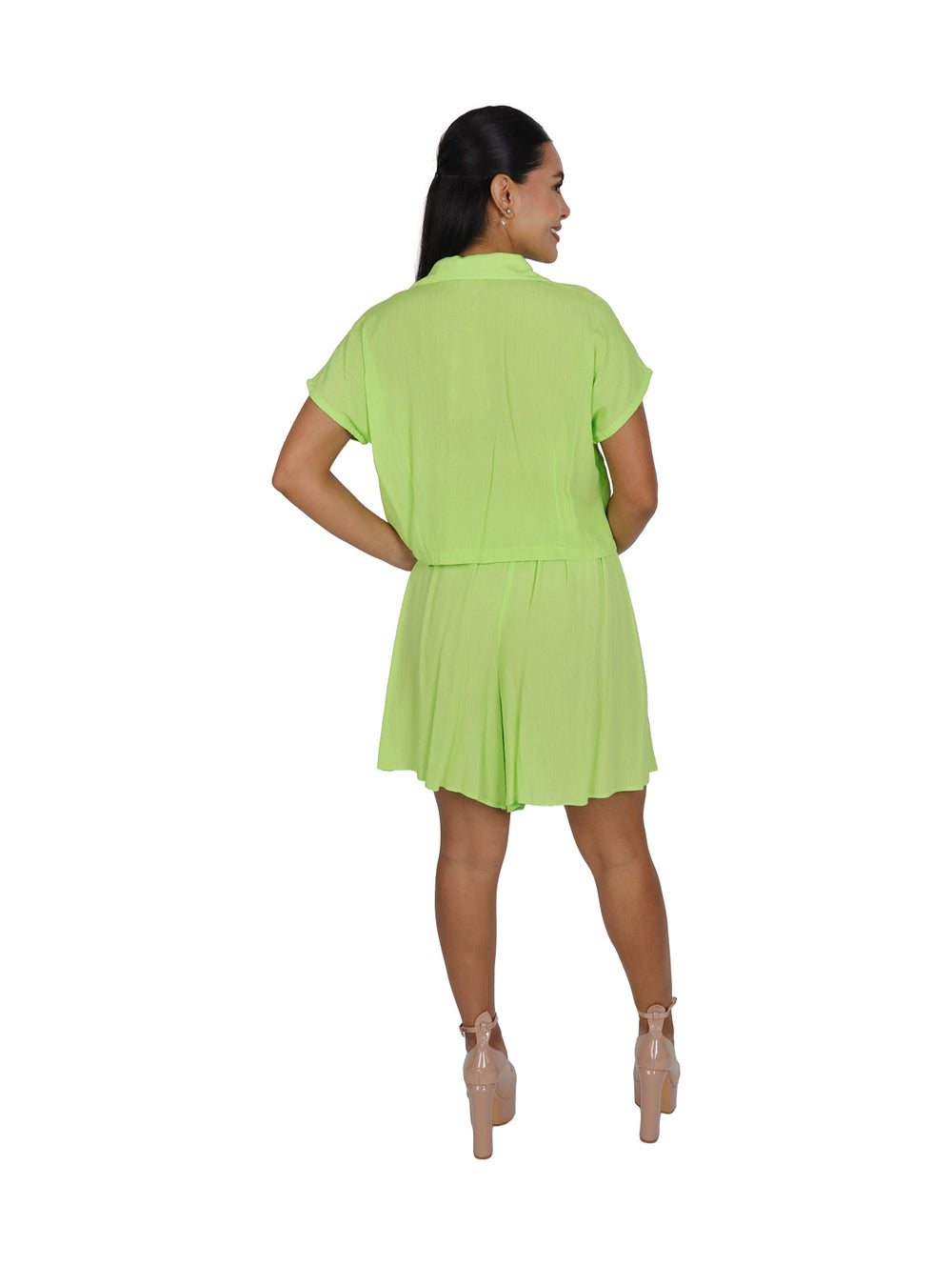 Mujer vistiendo un conjunto de dos piezas en color verde brillante compuesto por camisa y falda corta.