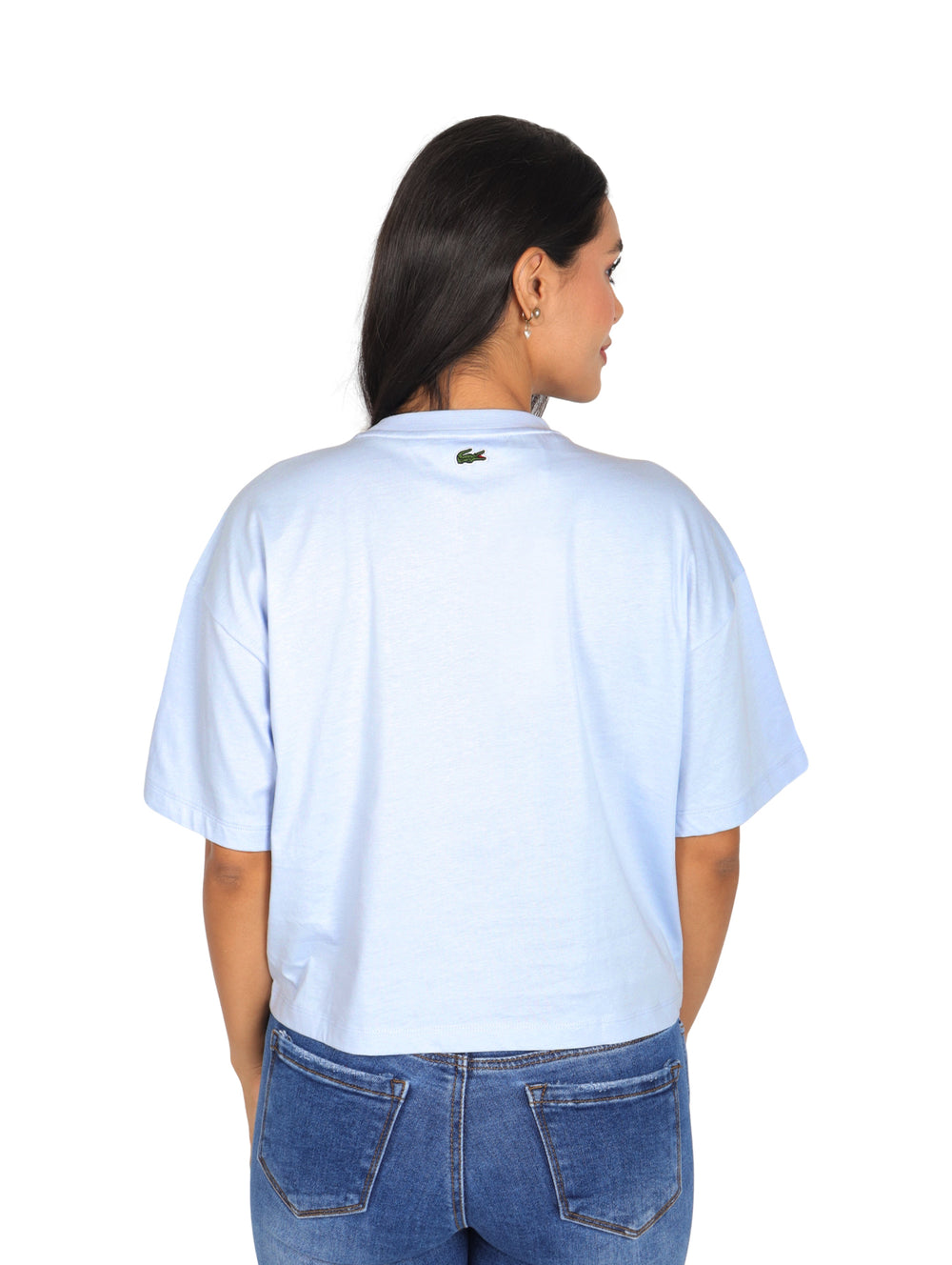 Mujer vistiendo una camiseta Lacoste de color azul claro con corte boxy y cuello redondo.
