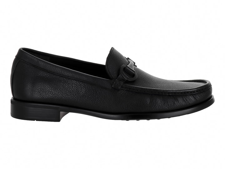 Zapato mocasín de cuero negro para hombre con detalle de hebilla y textura granulada.