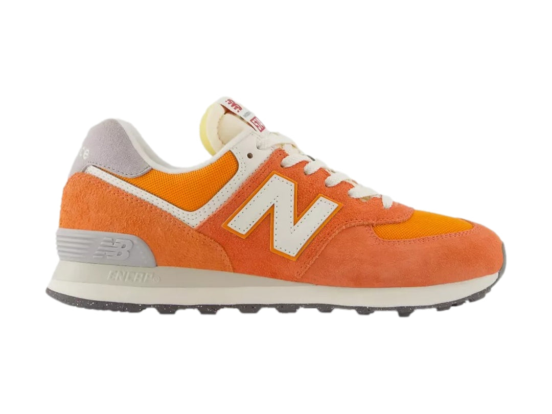 Tenis New Balance modelo 574 en color naranja atómico con detalles en blanco y gris.