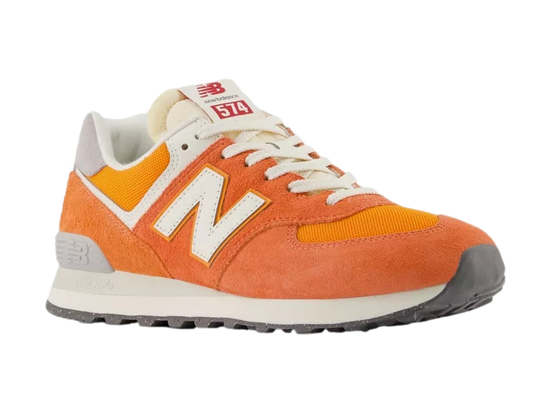 Tenis New Balance modelo 574 en color naranja atómico con detalles en blanco y gris.