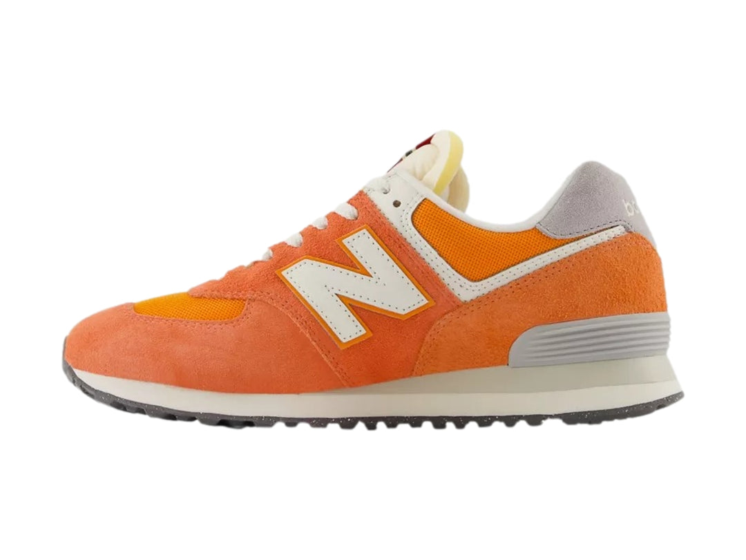 Tenis New Balance modelo 574 en color naranja atómico con detalles en blanco y gris.