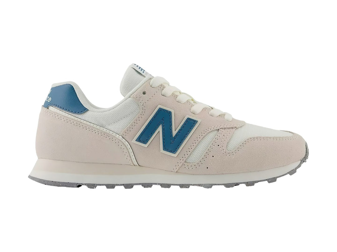 Tenis New Balance color beige Moonbeam con detalles en azul y suela blanca.