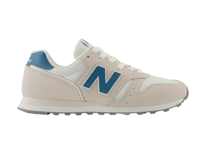Tenis New Balance color beige Moonbeam con detalles en azul y suela blanca.